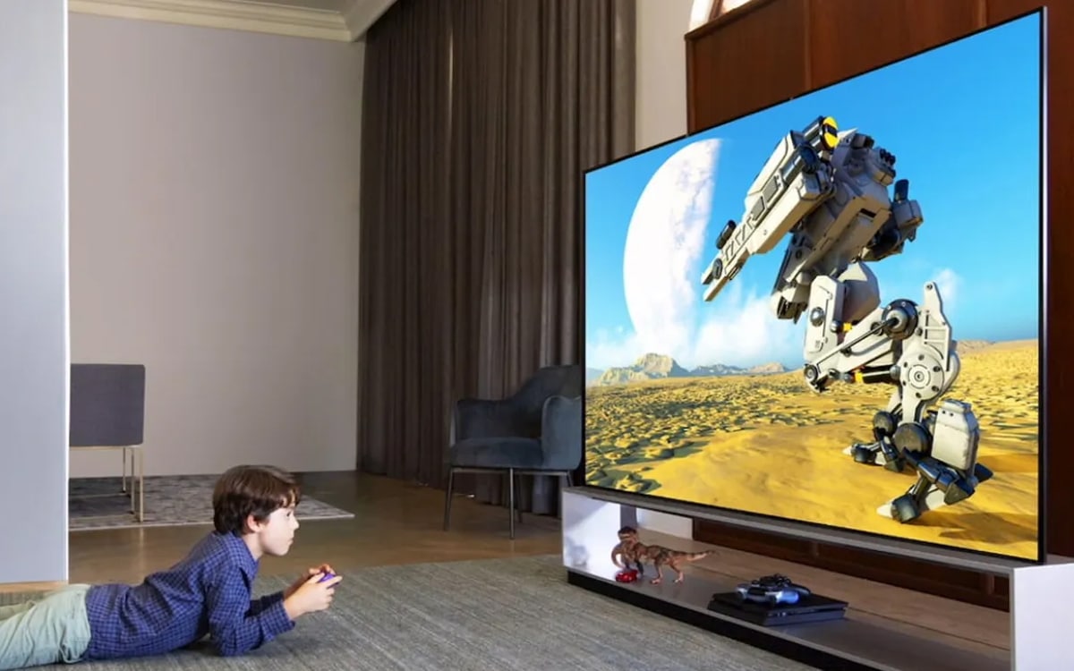 A boy focused on playing video games on a large television screen